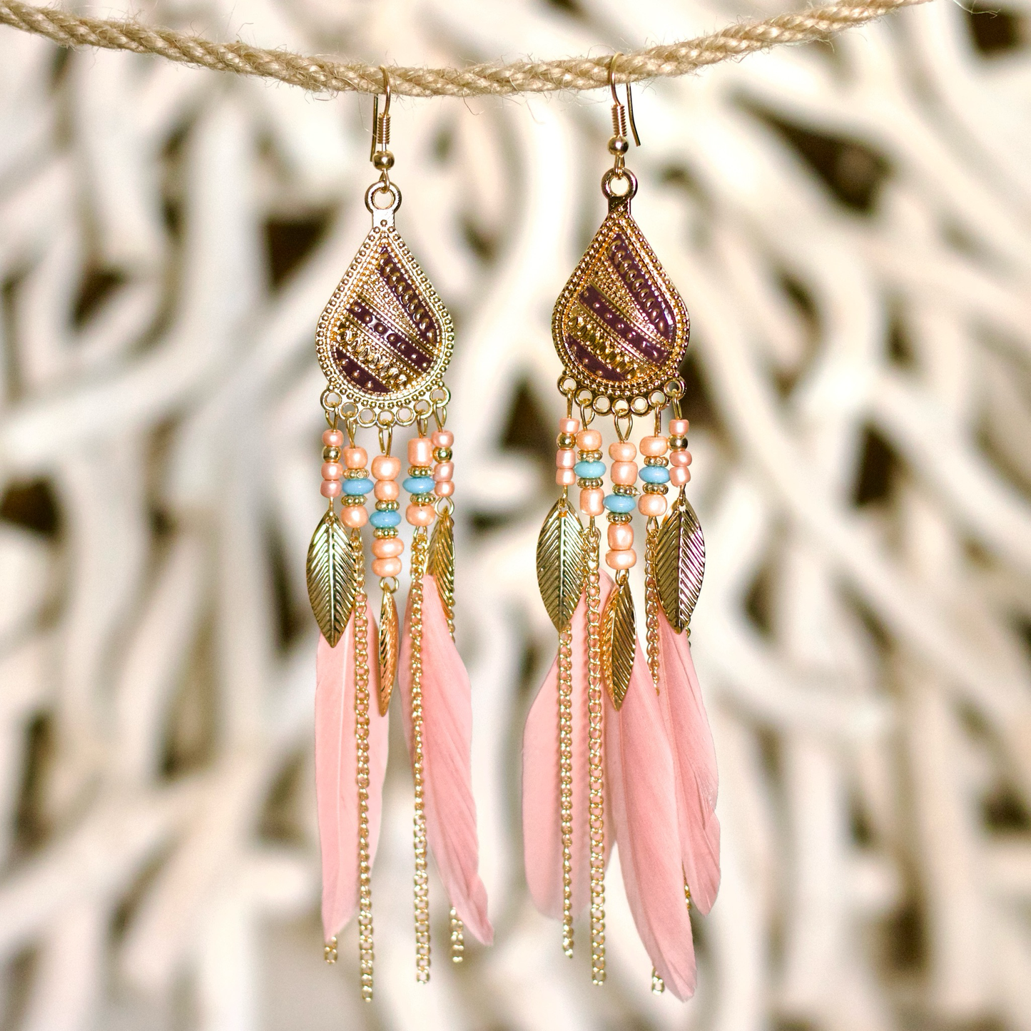 Bohemian-style statement earrings with soft pink feathers